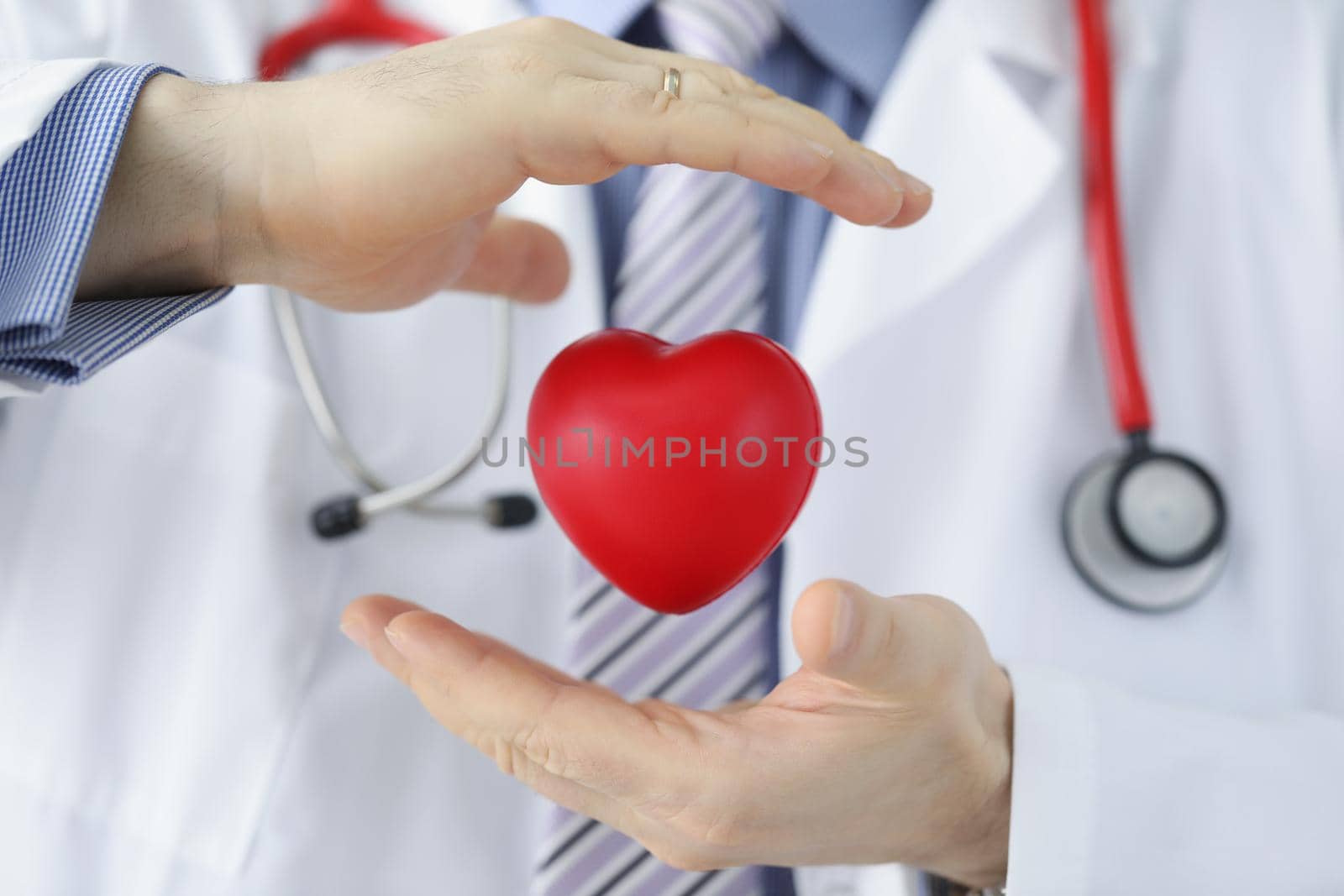 Medical worker protect plastic red heart, doctor cover heart model with hands by kuprevich