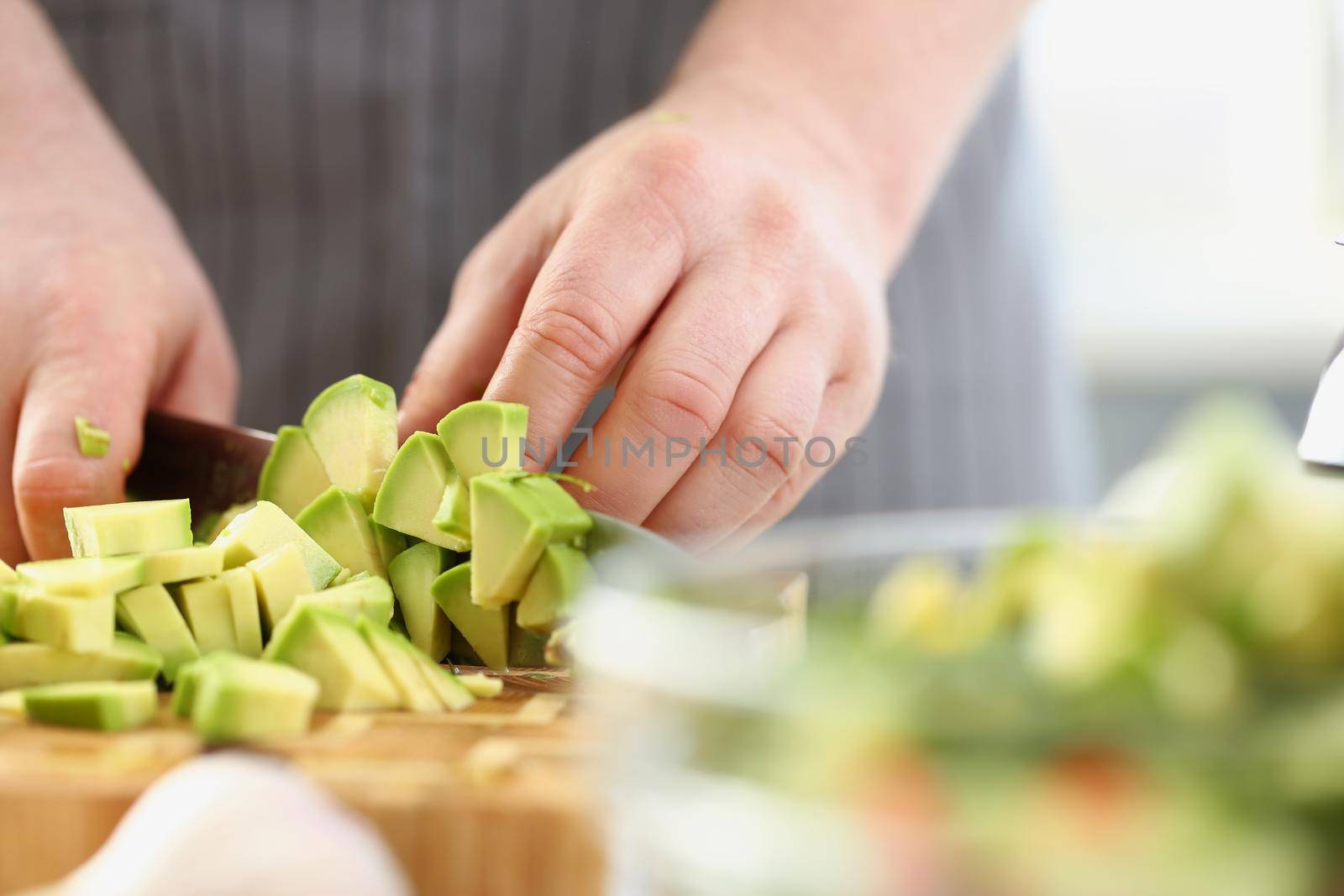 Man cutting mellow avocado on cutting board, inspiration to cook tasty dinner by kuprevich