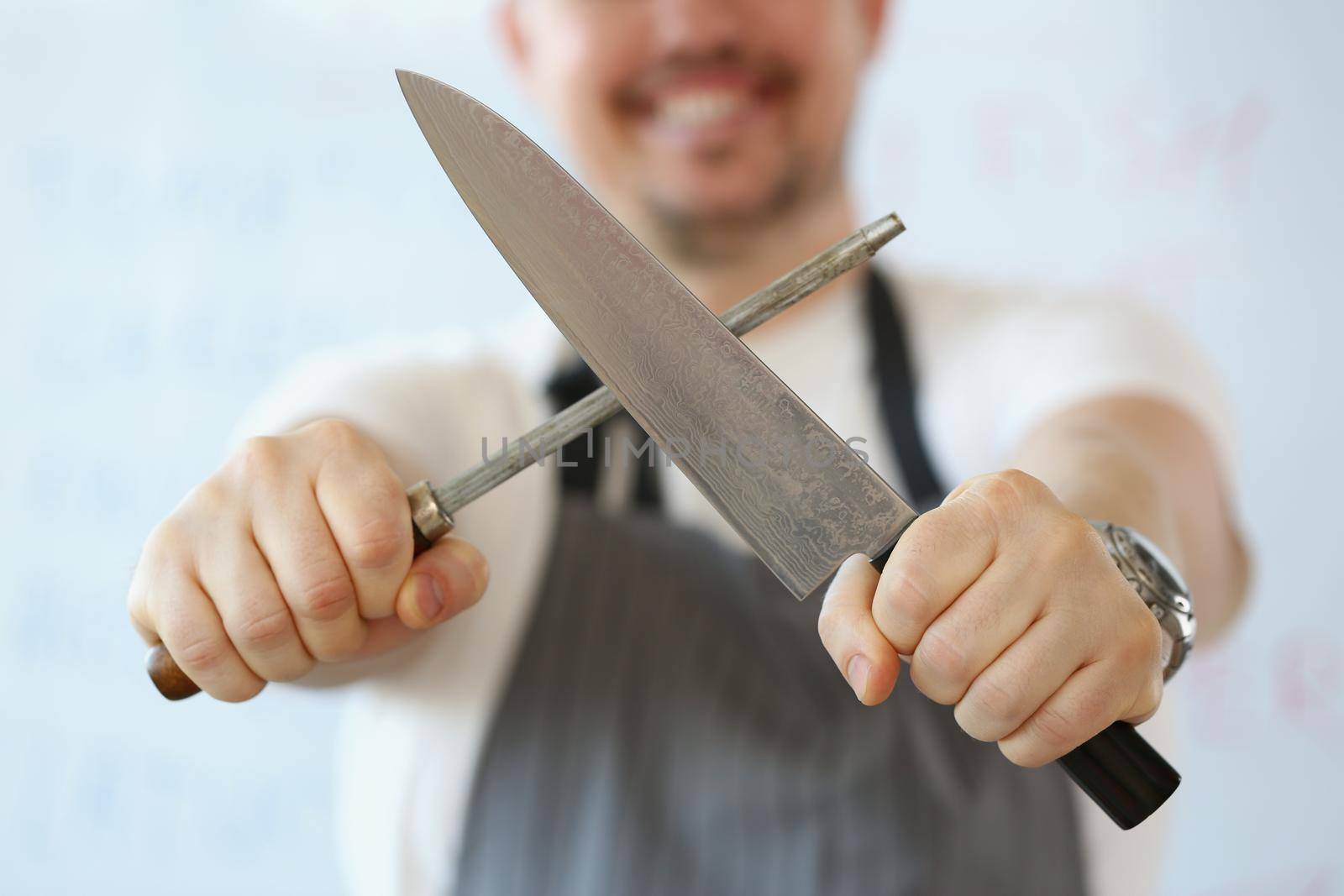 Standing man holding in hand sharp kitchenware for cooking, knife sharpening process by kuprevich