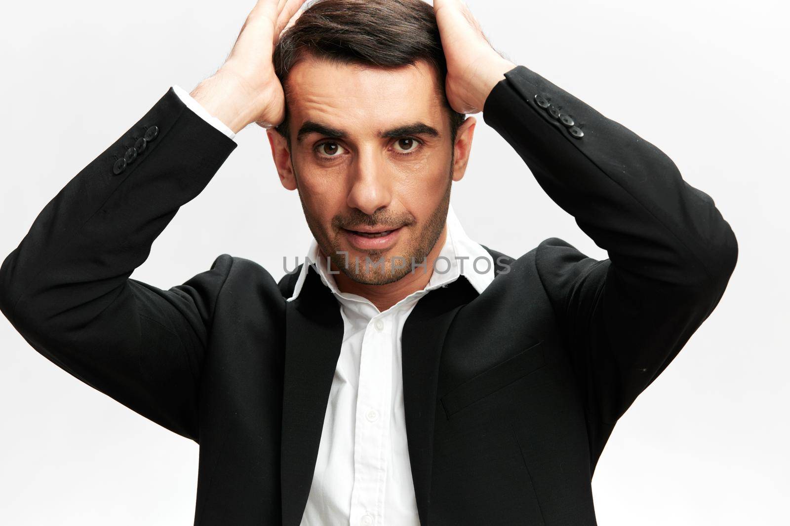 man holding his head in a black business suit close-up workflow light isolated background by SHOTPRIME