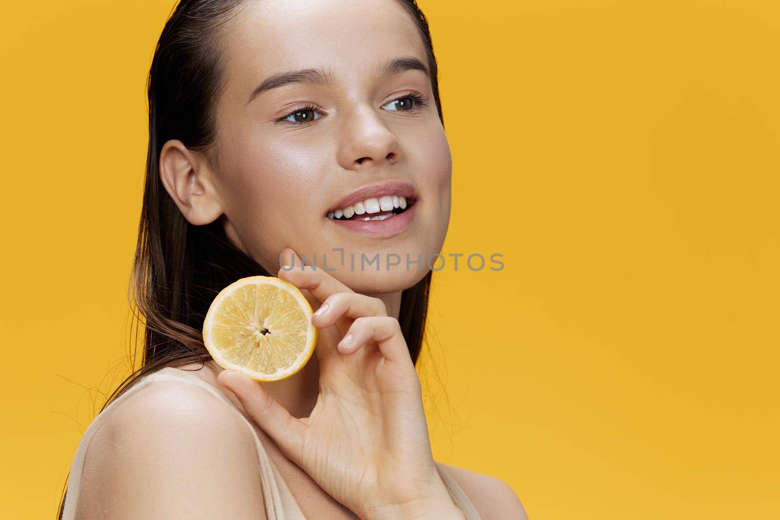 portrait woman lemon in hands posing clean skin yellow background. High quality photo