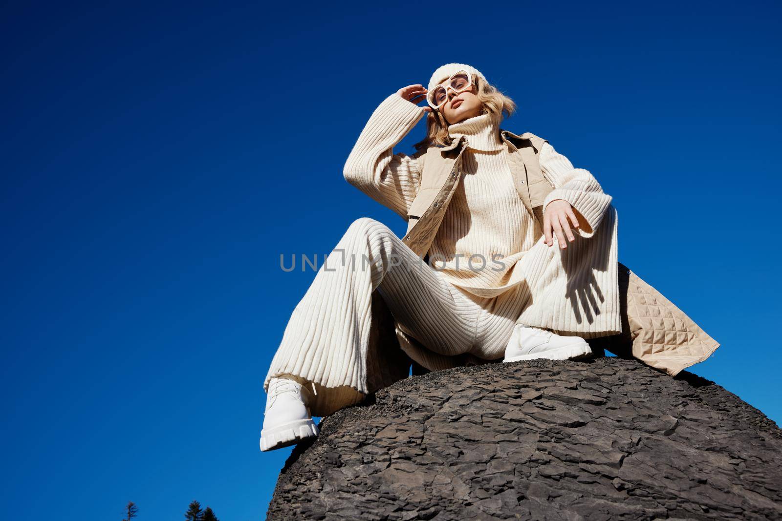 young woman in autumn clothes stands on a rock landscape blue sky lifestyle. High quality photo