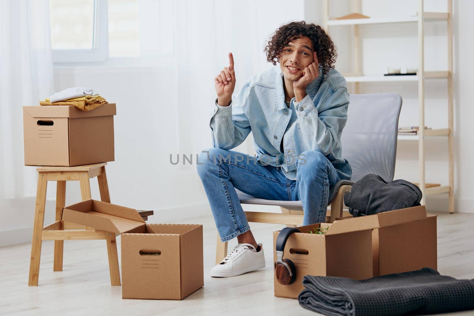 guy with curly hair unpacking things from boxes in the room Lifestyle. High quality photo