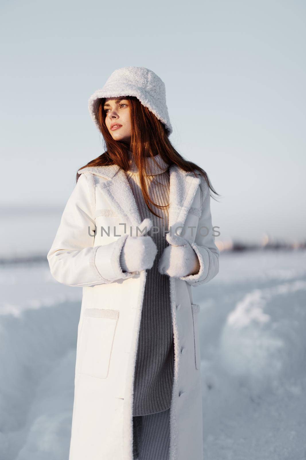 young woman in a white coat in a hat winter landscape walk Fresh air. High quality photo