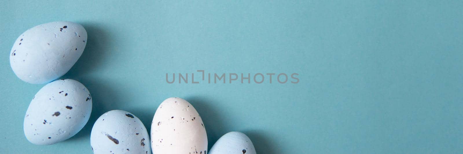 Easter background. Blue and white painted quail eggs on a blue background, decorated with cotton. Happy Easter holiday.