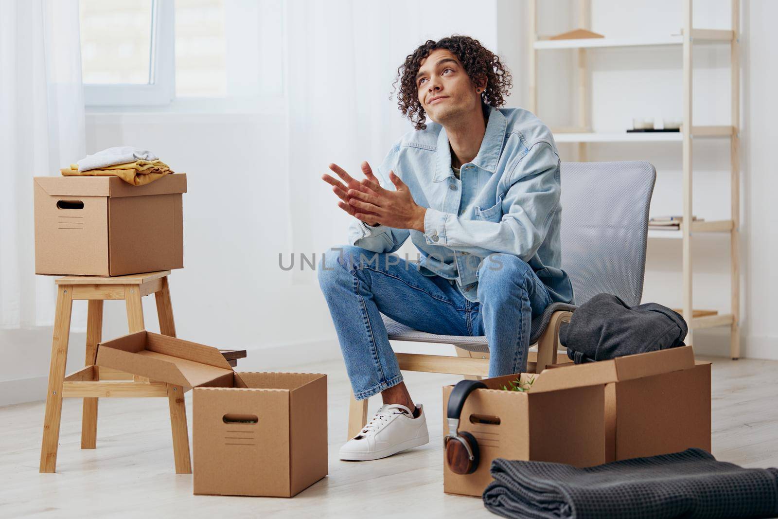 handsome guy sitting on a chair with boxes interior moving interior. High quality photo