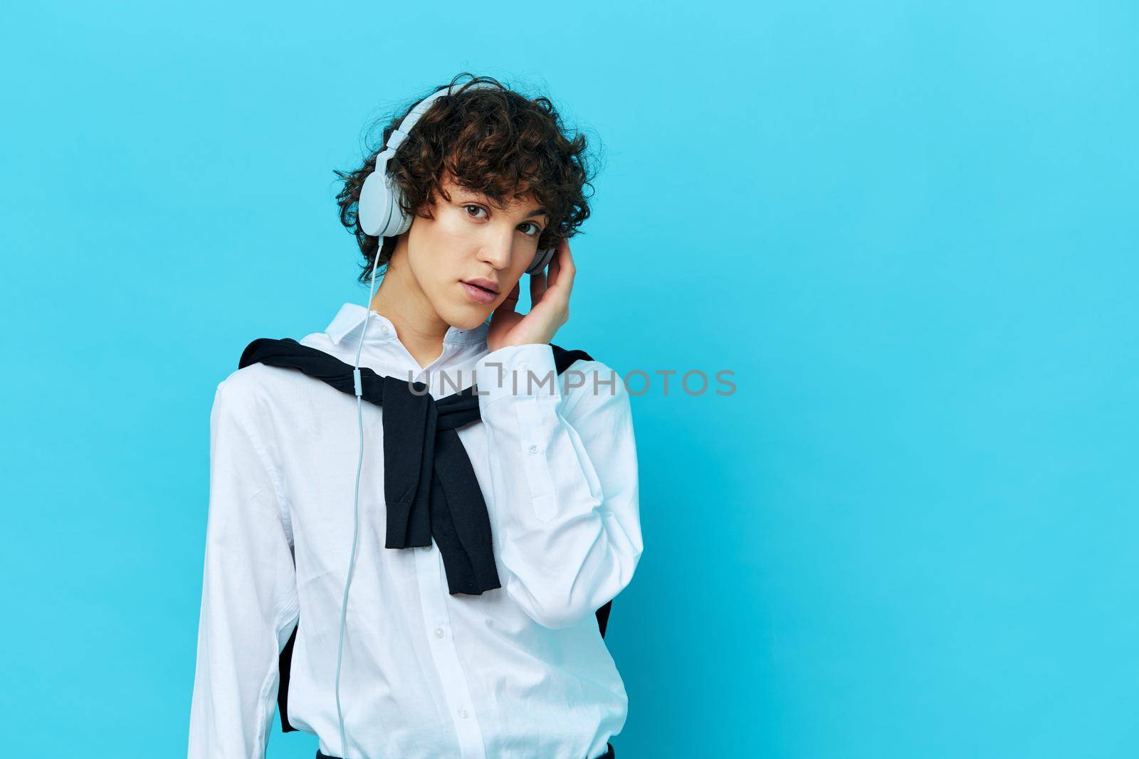 curly guy technology headphones in a white shirt with sweater blue background. High quality photo
