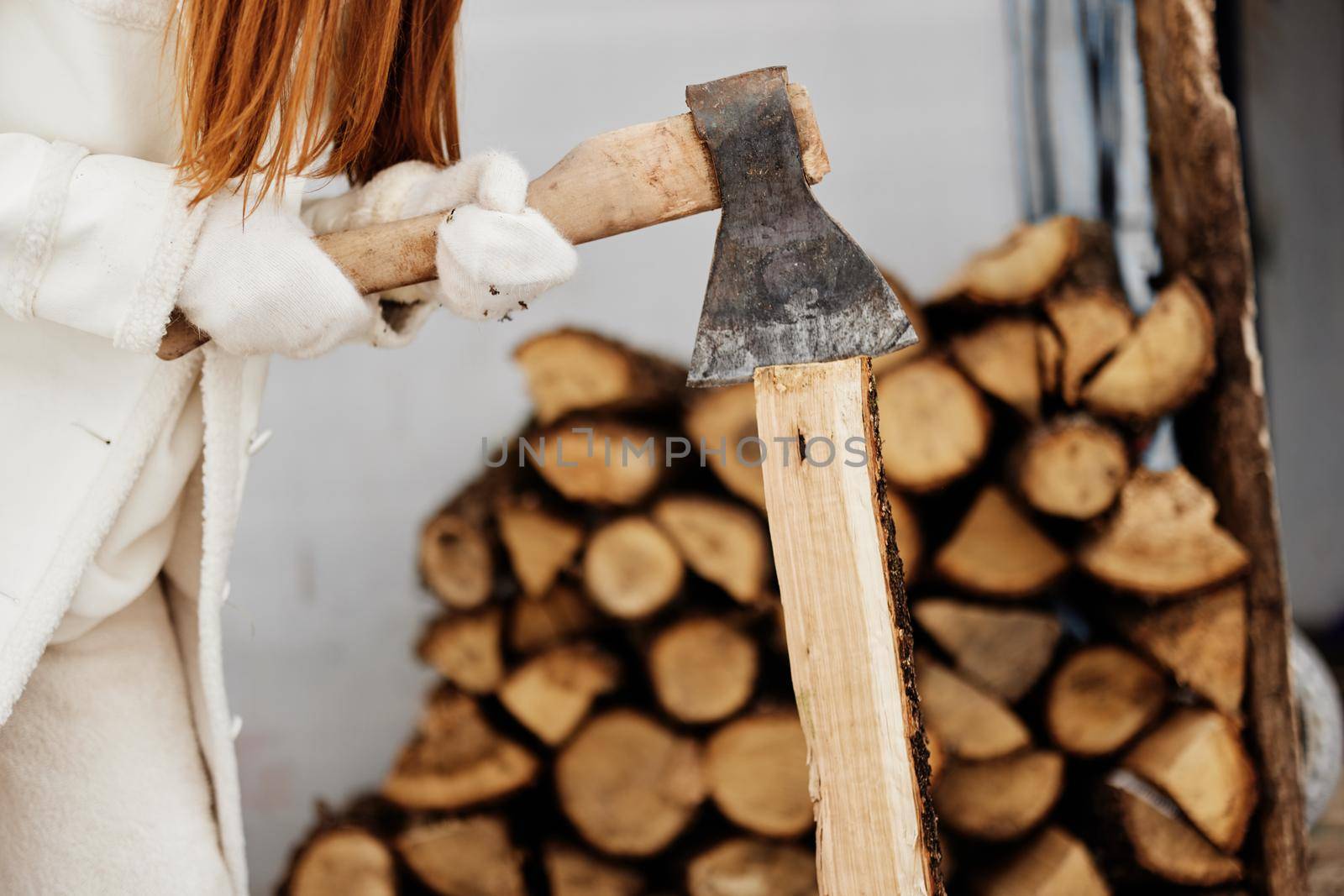 portrait of a woman sitting next to firewood heating winter nature winter holidays by SHOTPRIME