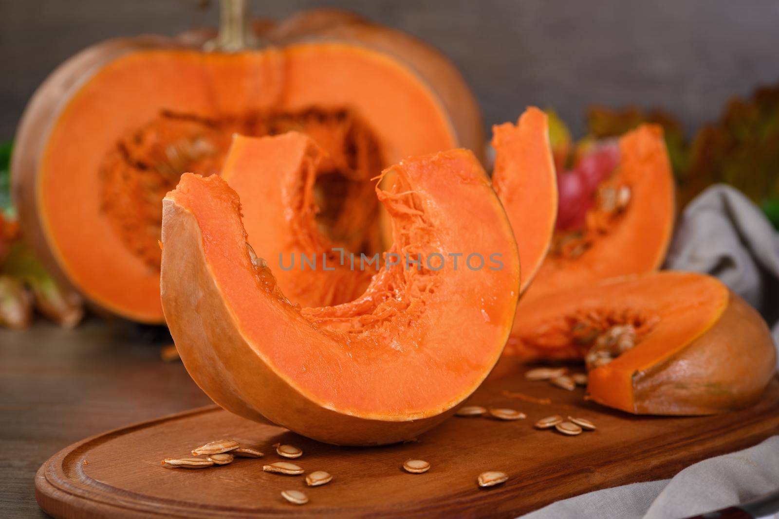 Whole fresh orange big pumpkin and slice of pumpkin on wooden board, closeup. Organic vegetable product, ingredients for cooking, healthy food vegan