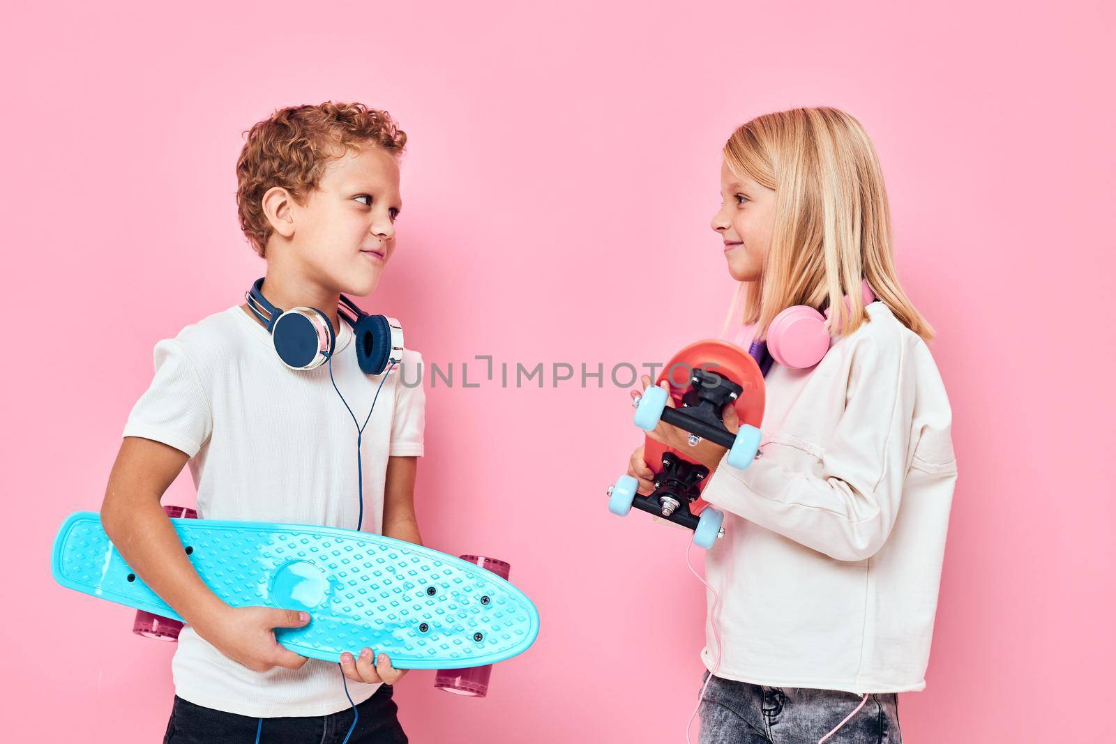 Stylish little boy and cute girl in headphones skateboards in hands active lifestyle childhood. High quality photo