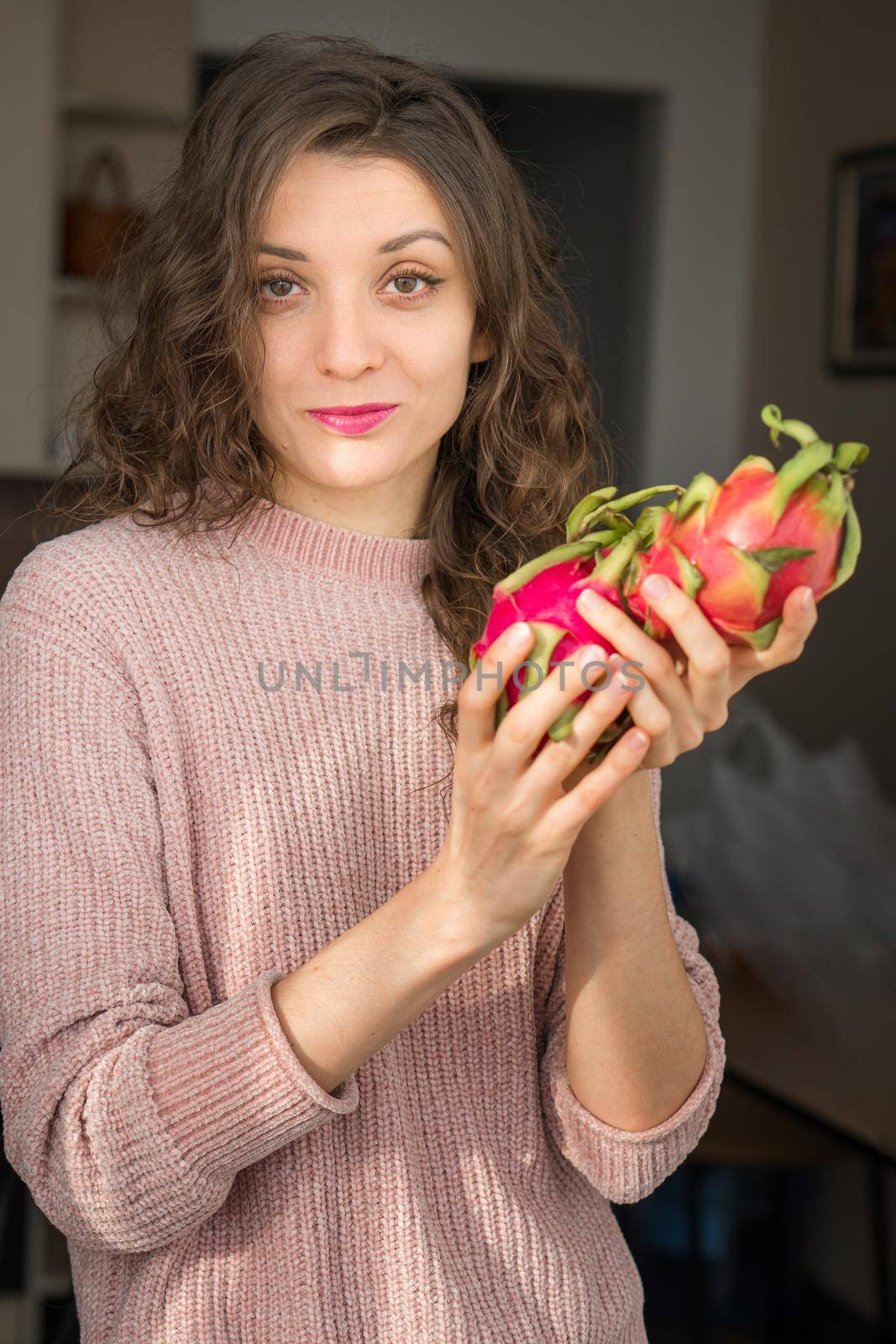 Young girl is holding two fresh ripe organic dragon fruits or pitaya, pitahaya. Exotic fruits, healthy eating concept.