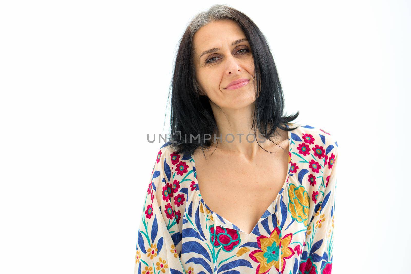 Close-up portrait of middle aged woman starting getting grey-haired wearing dress with flowers on white background, middle age sexy lady, cosmetology concept.