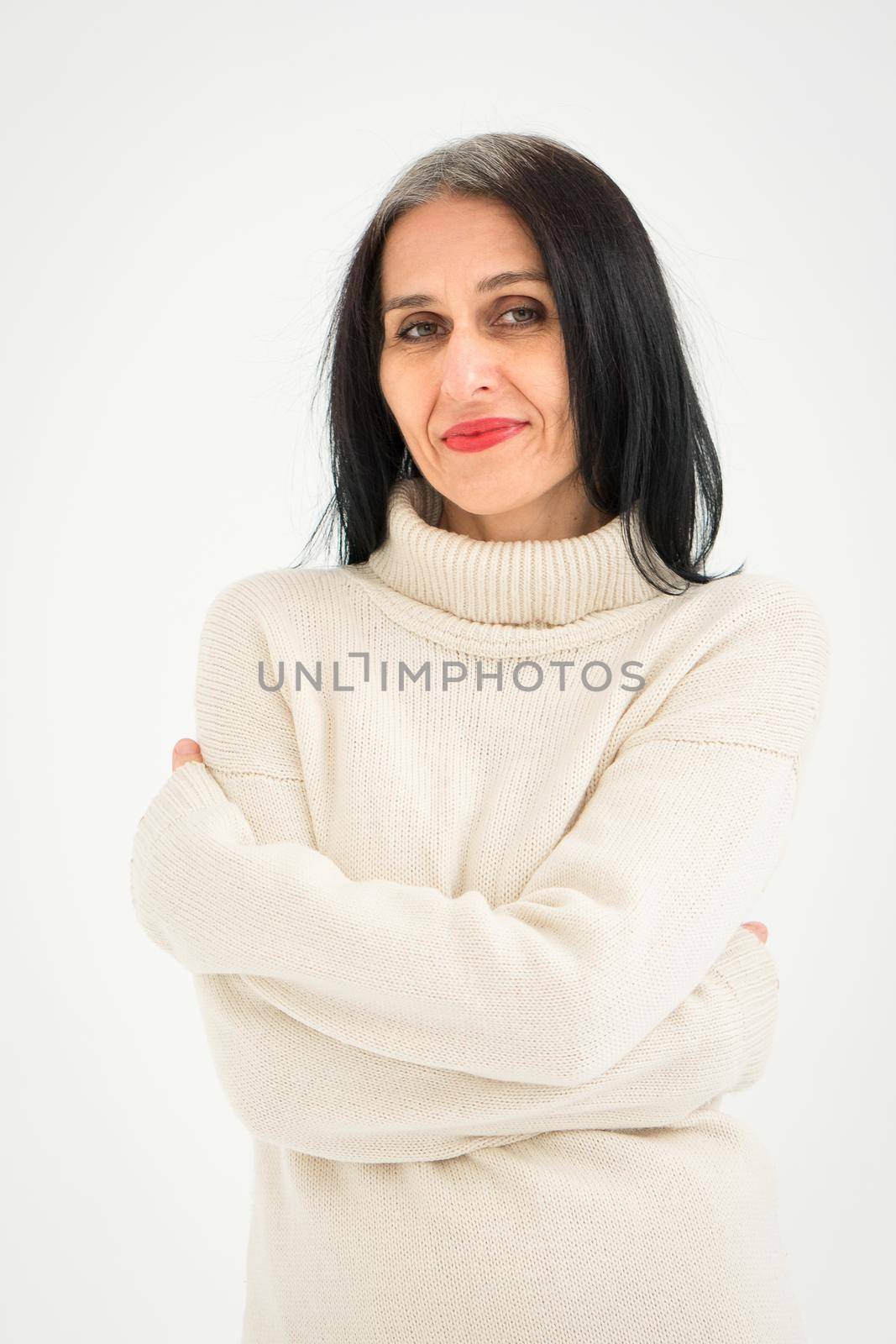 Middle aged woman starting getting grey-haired is posing in studio in sweater on white background, face skin care beauty, middle age skincare cosmetics, cosmetology concept by balinska_lv