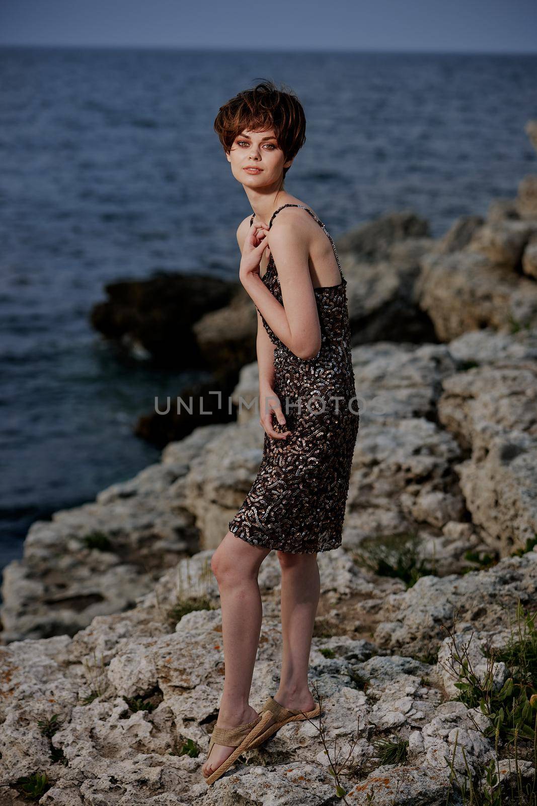 short haired woman standing on stones posing in beach dress Lifestyle. High quality photo