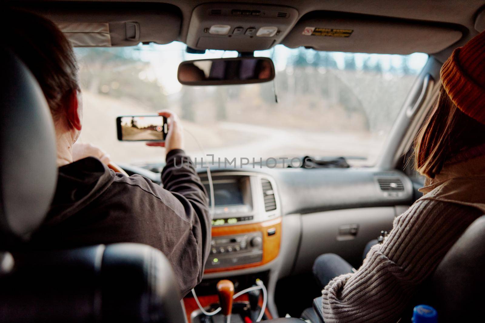 a woman driving a car with a phone shoots a video. High quality photo