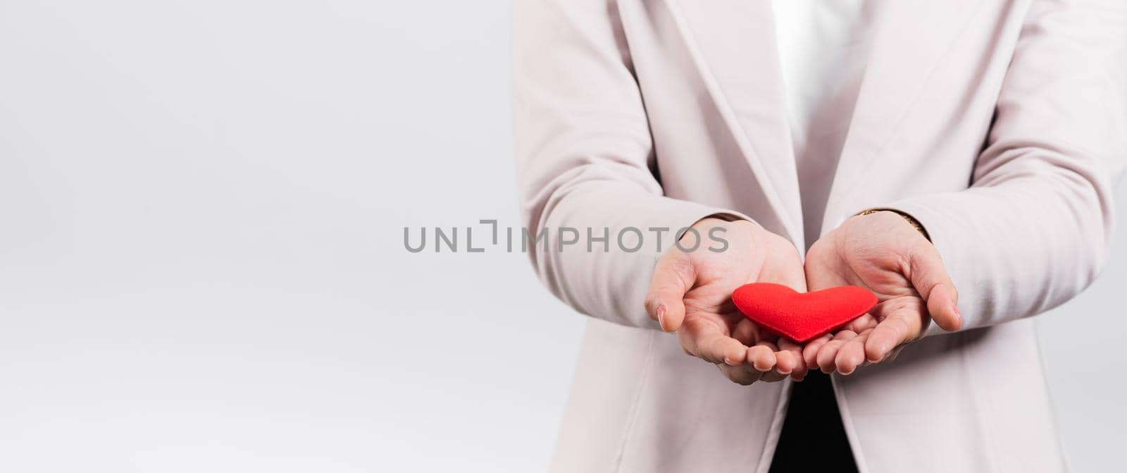 Smiling woman confidence showing holding red heart with her hand palm isolated white background by Sorapop