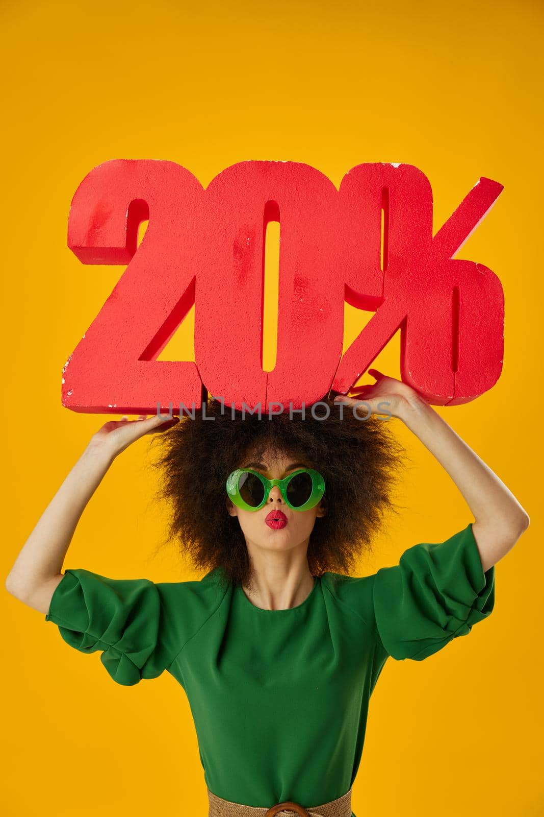 Pretty young female curly hairstyles green dress twenty percent discount yellow background unaltered. High quality photo