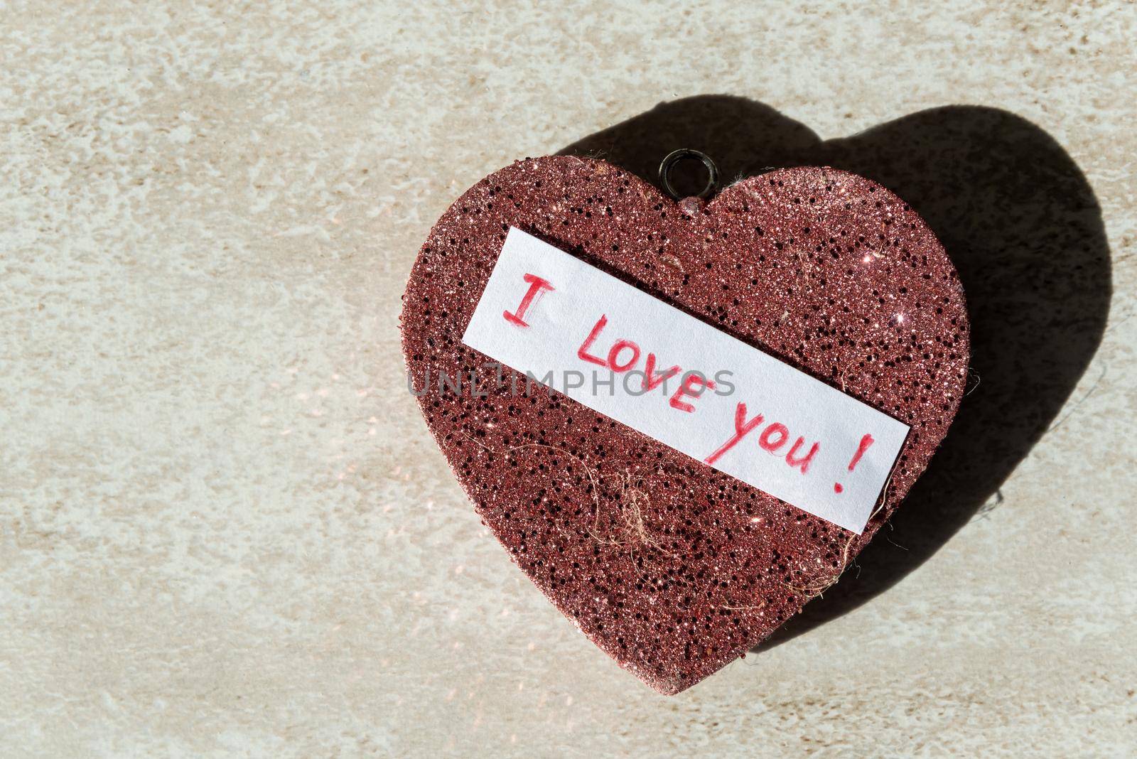 keychain in the shape of a red heart with sparkles and the inscription I love you close-up by karpovkottt