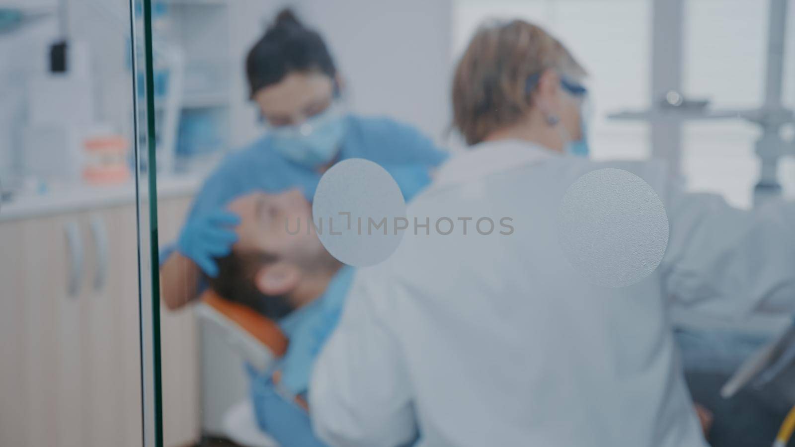 Dentist and nurse using dental drill machine to treat caries by DCStudio