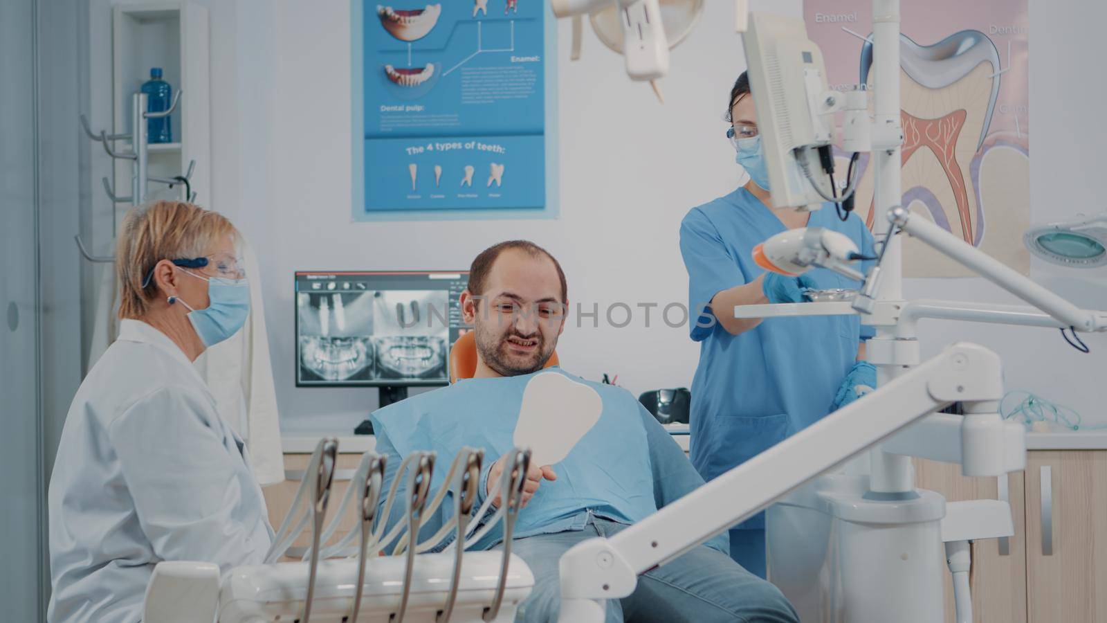 Patient holding mirror to see teeth alignment after dental procedure by DCStudio