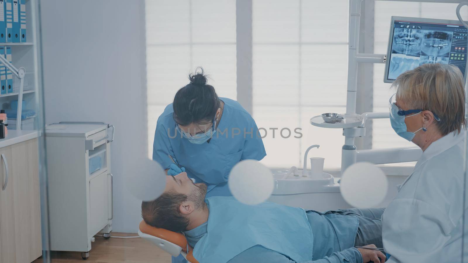 Team of experts extracting tooth at oral care clinic by DCStudio