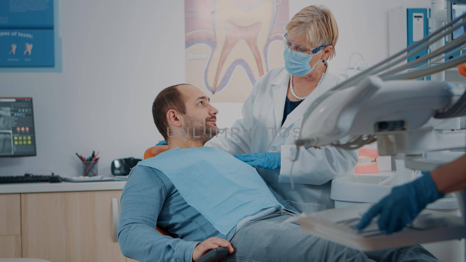 Patient opening mouth and dentist examining dentition work after surgery. Stomatologist doing oral care consultation with instruments, treating man at stomatology checkup appointment.