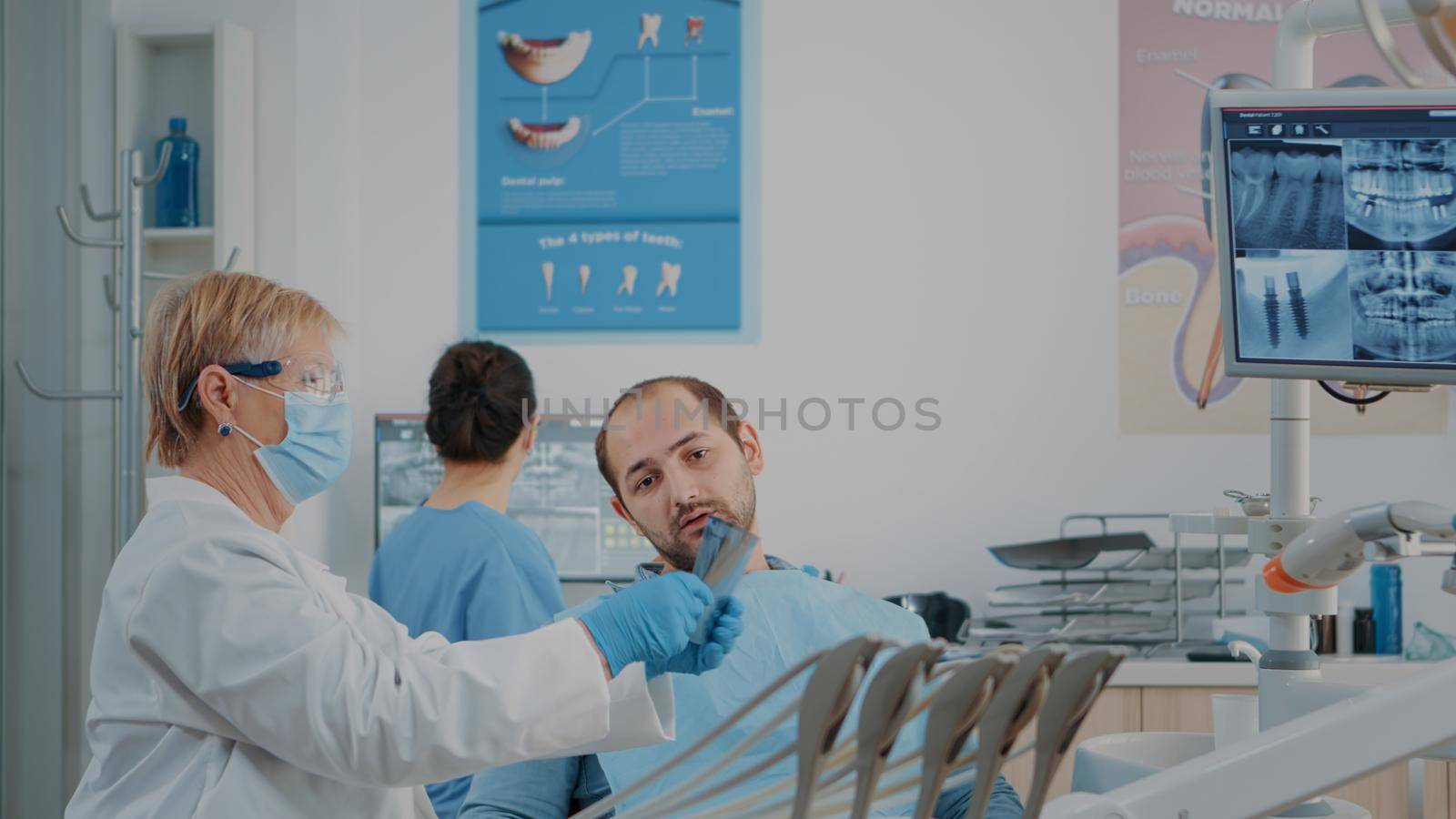 Senior dentist explaining teeth radiography to patient with caries problems. Stomatologist using x ray scan results to do dental examination and drill procedure at dentistry checkup.