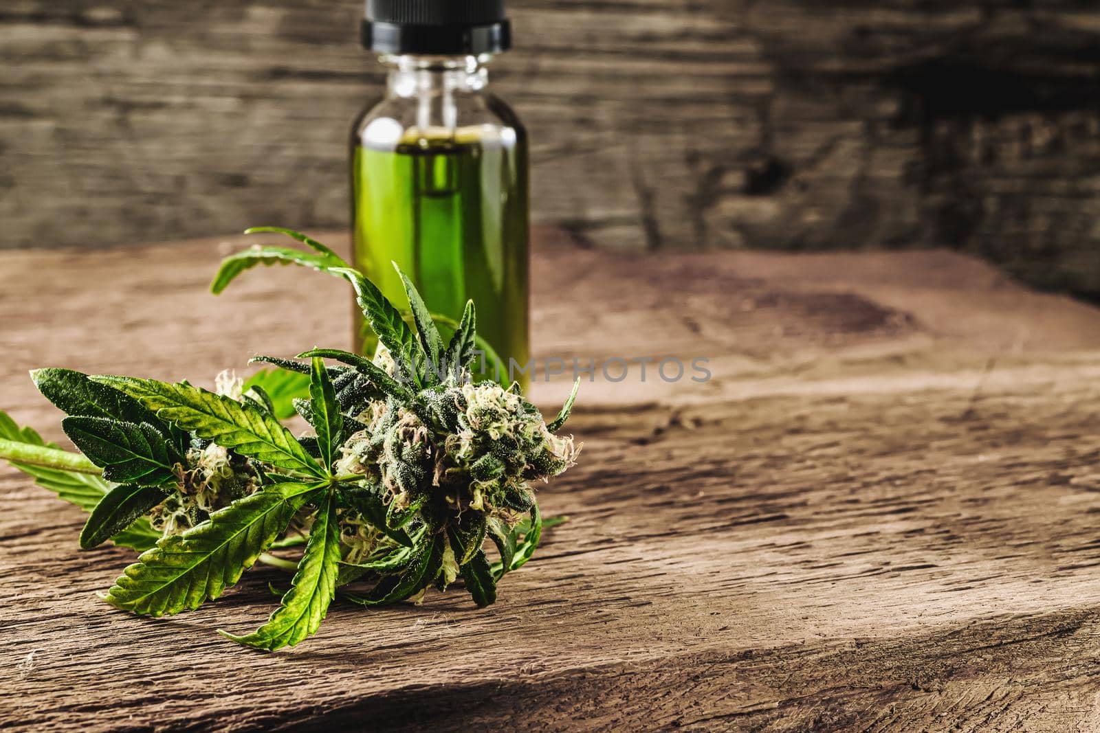 Glass bottle with herbal organic medicine CBD concentrate, droplet dosing a biological and ecological hemp plant herbal pharmaceutical cbd oil from a jar and medical cannabis bud on wooden background. Horizontal orientation.