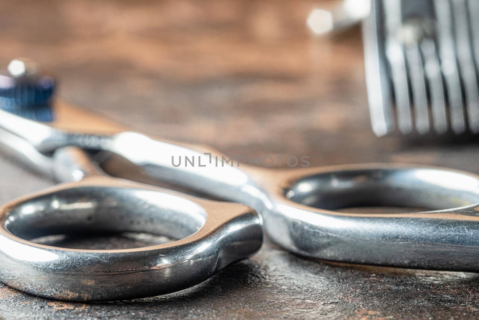 scissors for haircuts. Background part of a clipper in blur. Horizontal orientation. Rusty background. close-up.