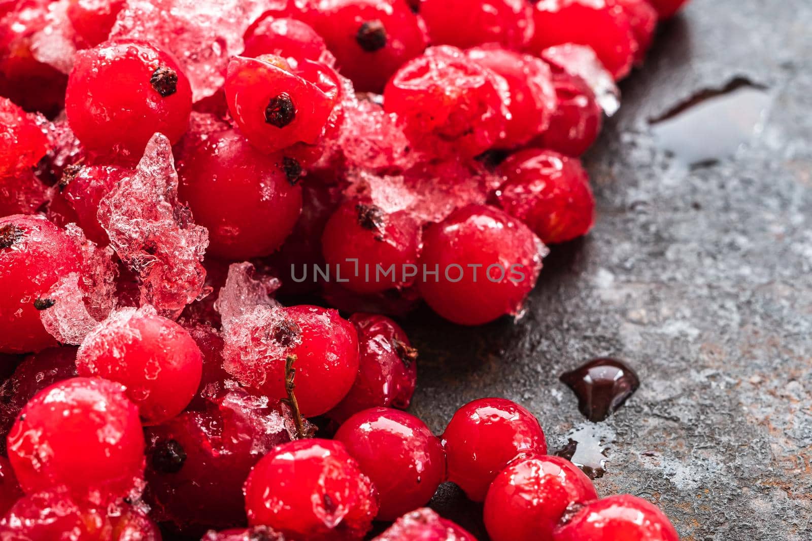 Frozen red currants closeup pile lie on a rusty surface. copy space. horizontal orientation.