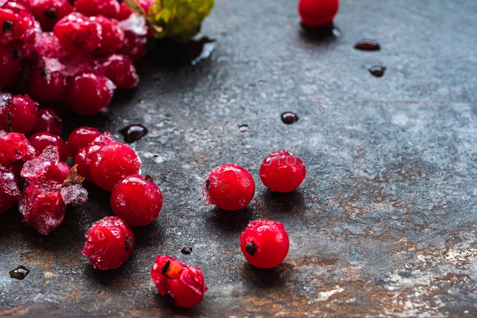 scattered frozen red currants closeup lie on a rusty surface. copy space. horizontal orientation.