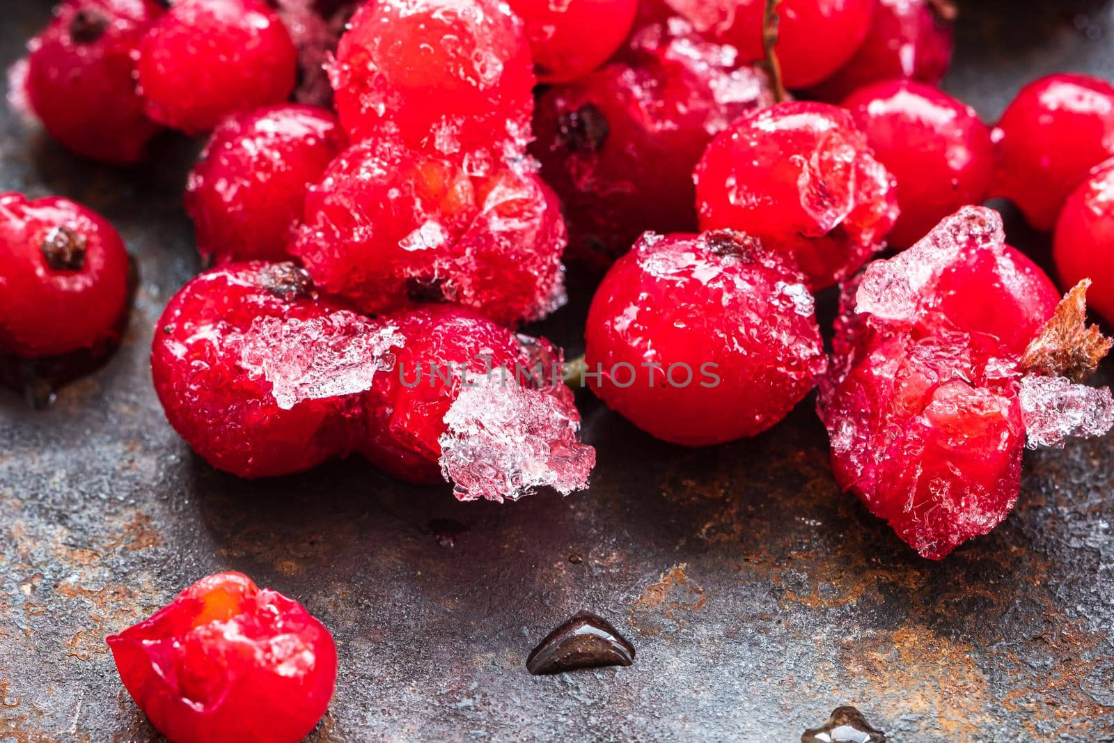 Frozen ice red currants pile lie on a rusty surface. horizontal orientation. close-up