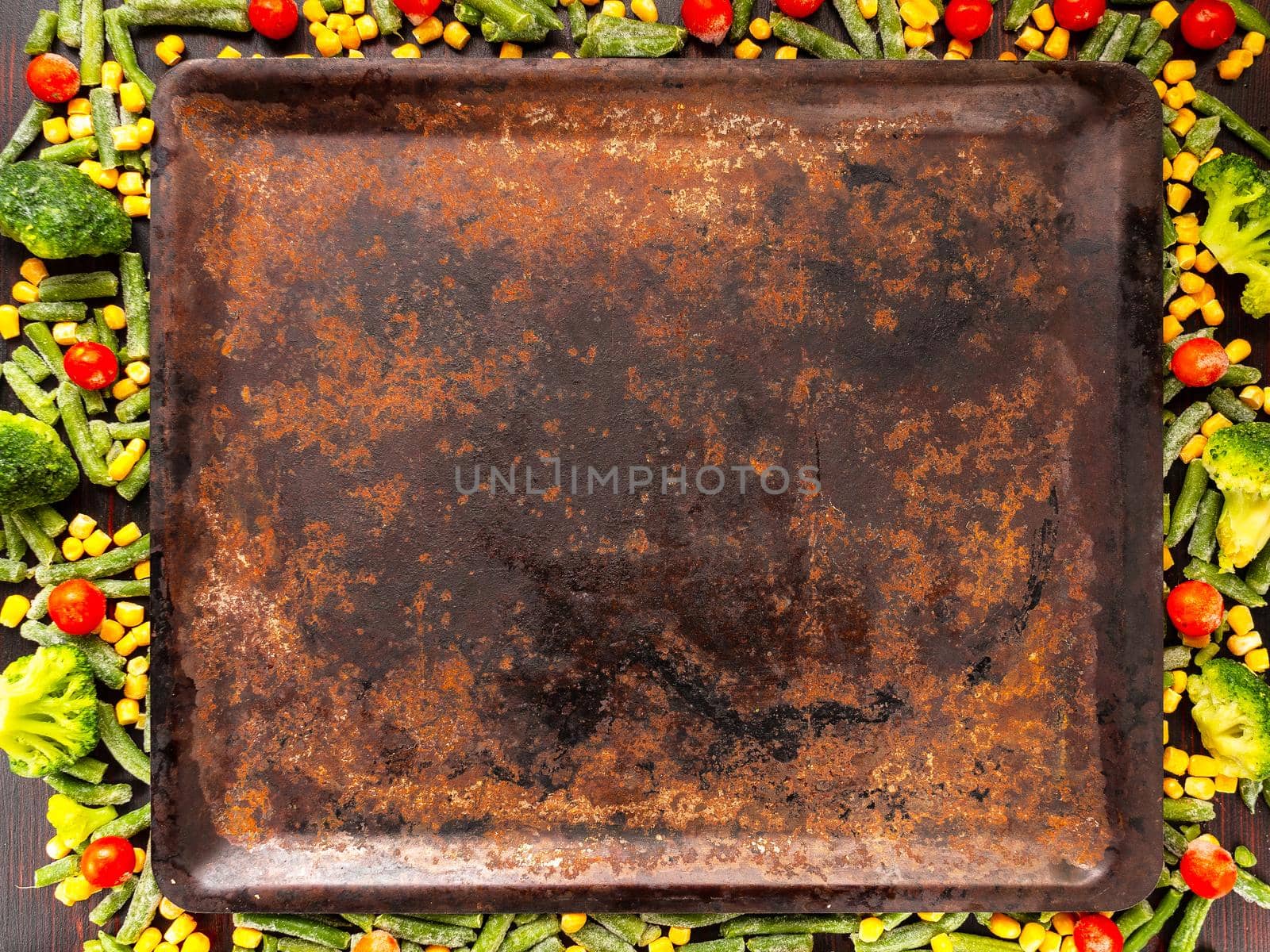 Food background with free space for text. broccoli, corn, green beans, tomatoes around a baking sheet. View from above.