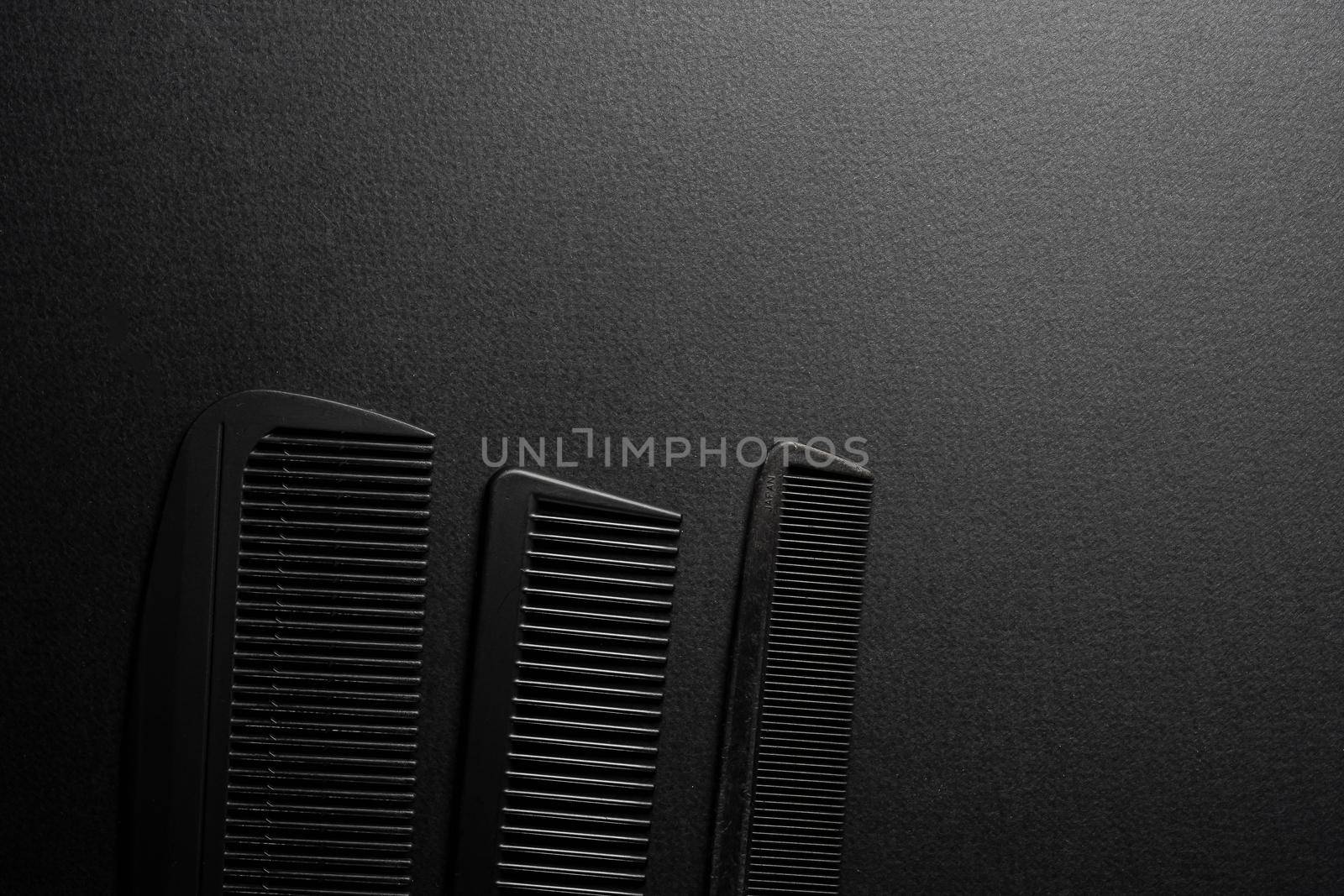 On a black surface are old barber tools. barber tools. three comb. black monochrome. frame. top view flate lay. copy space