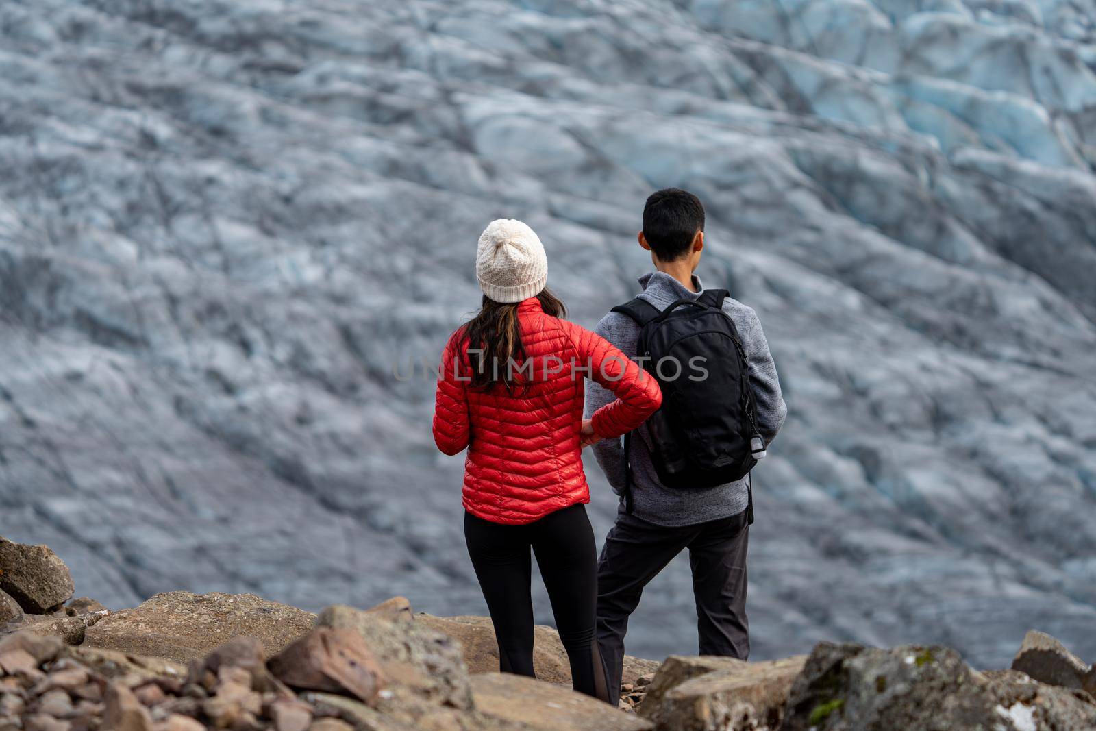 Unrecognizable tourist couple looking to the glacier, focus on foreground