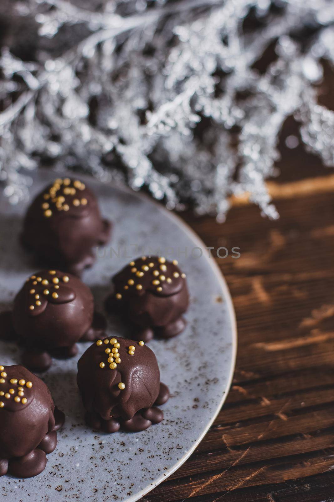 Dark chocolate handmade candy balls on handmade plate on dark wooden background with the cup of tea in a white cup.