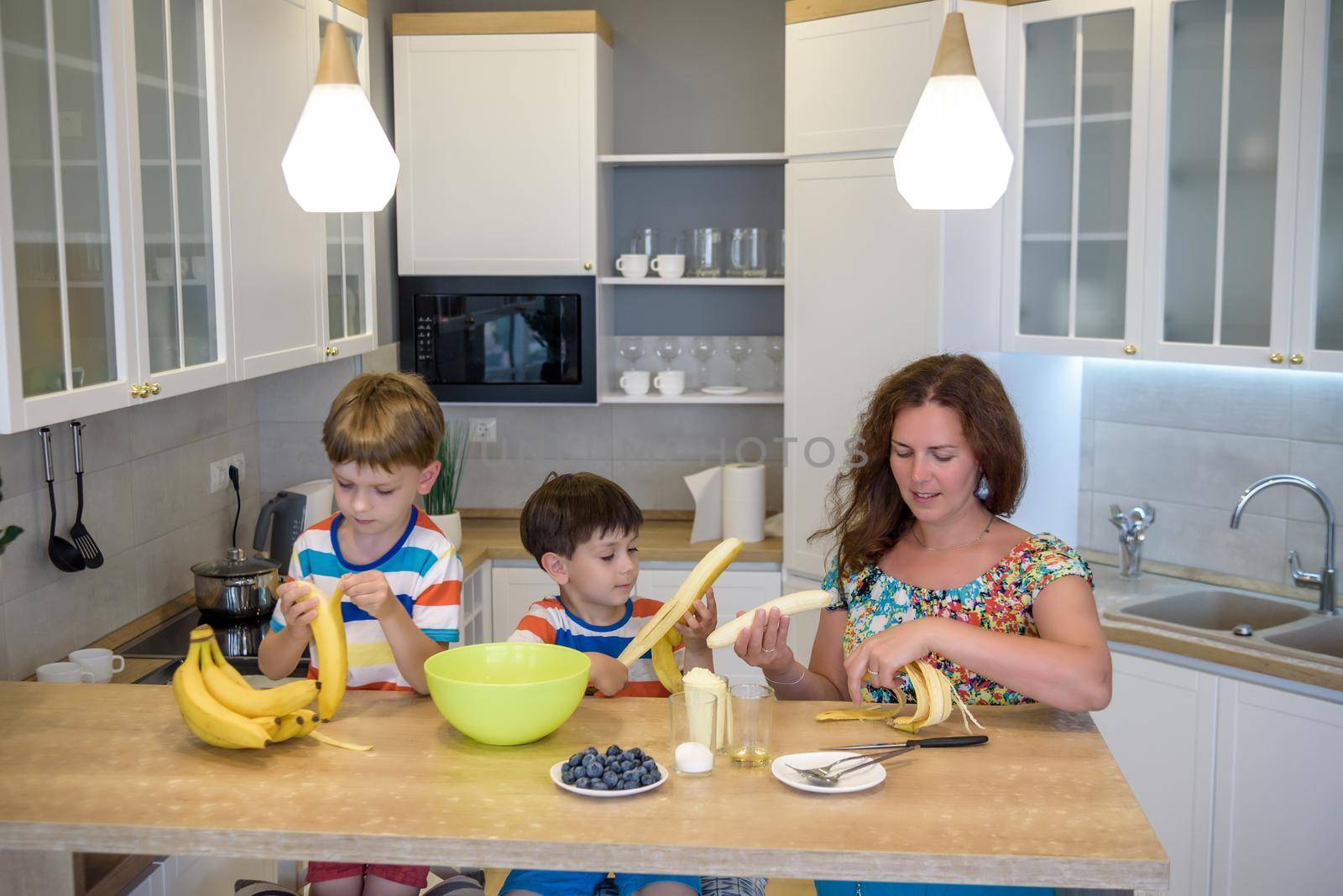 Young mother and her two kids at kitchen baking cookies.