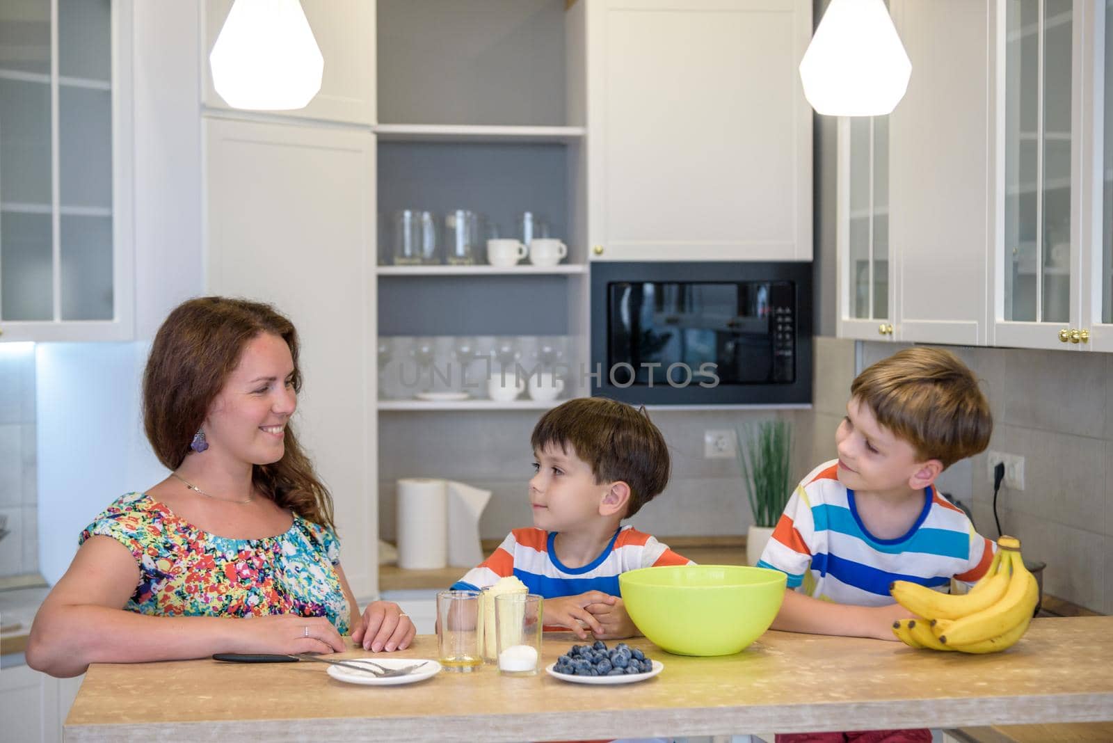 Young mother and her two kids at kitchen baking cookies.
