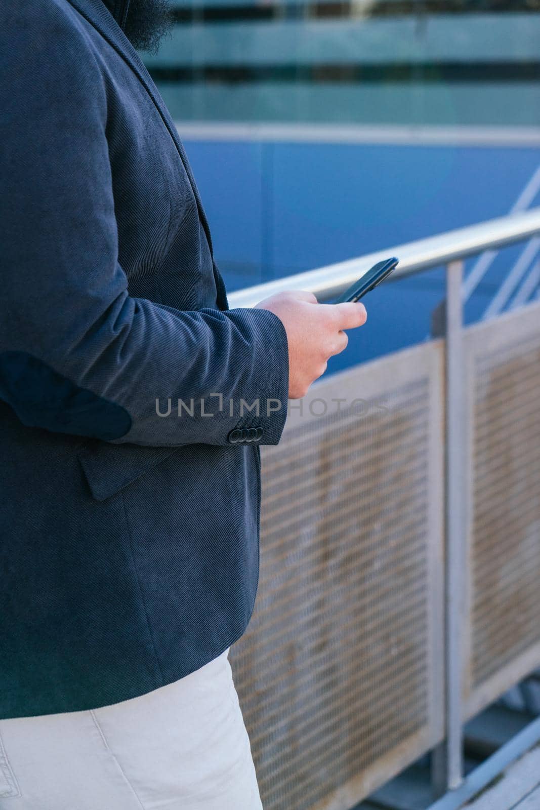 young business man looking phone near to office. Natural light in a sunny day.