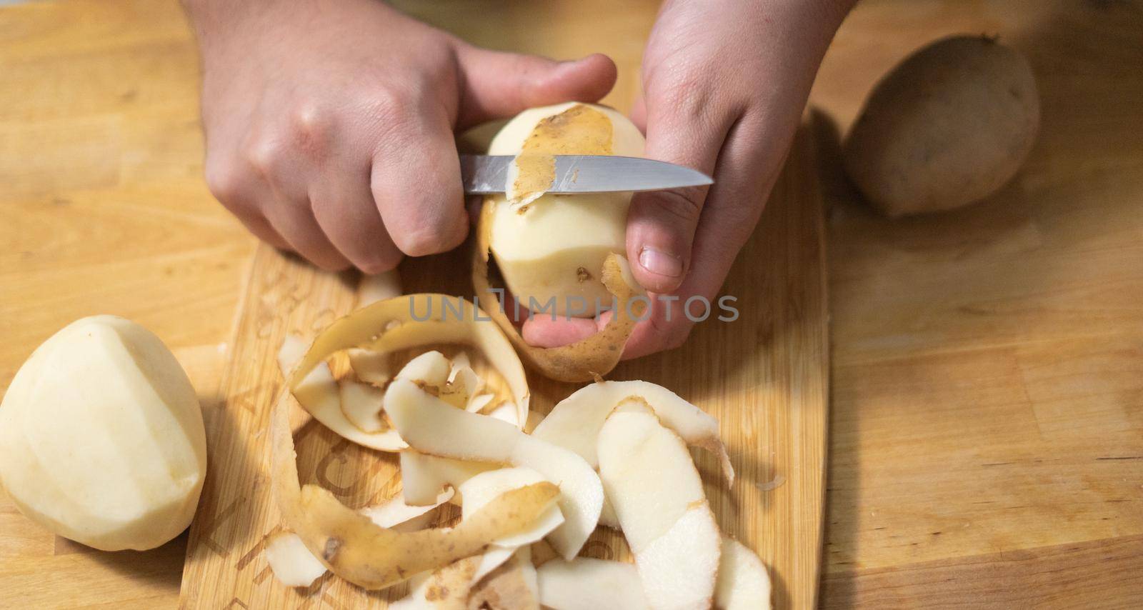 peeling a potato on a wooden table for savoury, omelette, vegan, vegetarian recipe