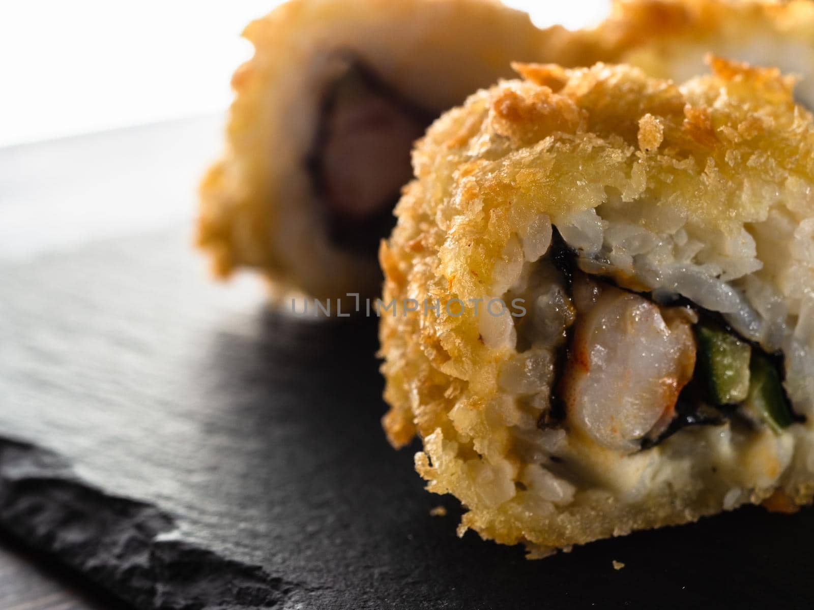 sushi rolls on gray stone slate on wood background. made by hand