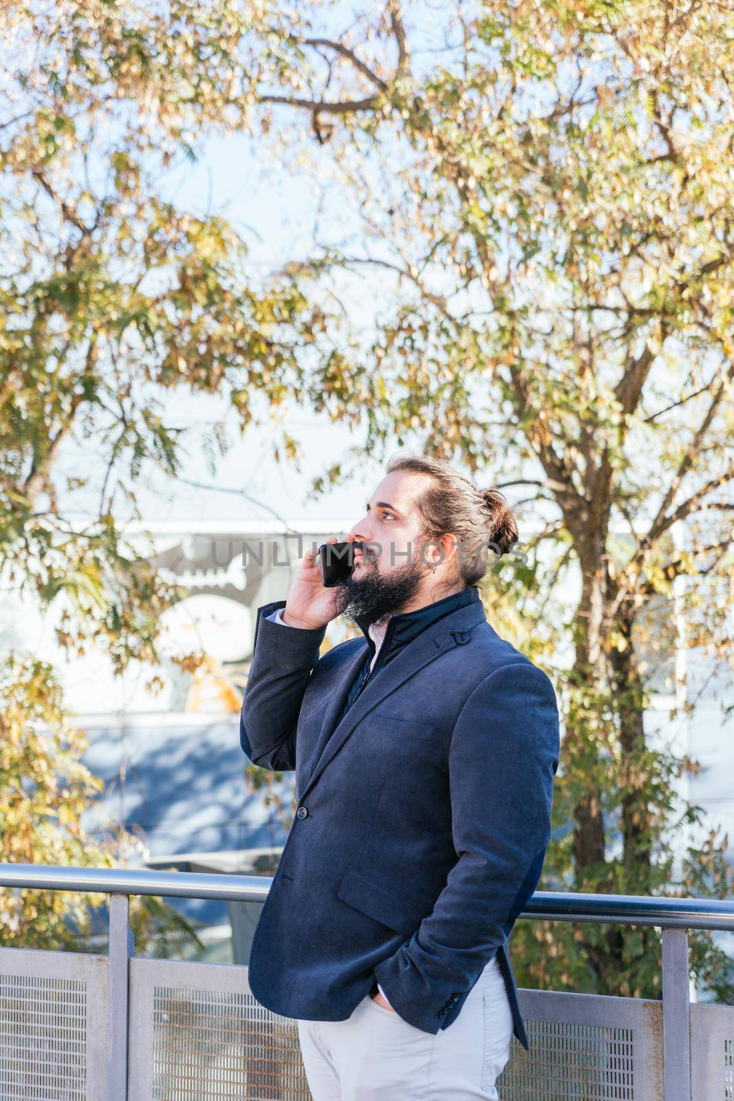 Young business man talking mobile next to the offices by CatPhotography