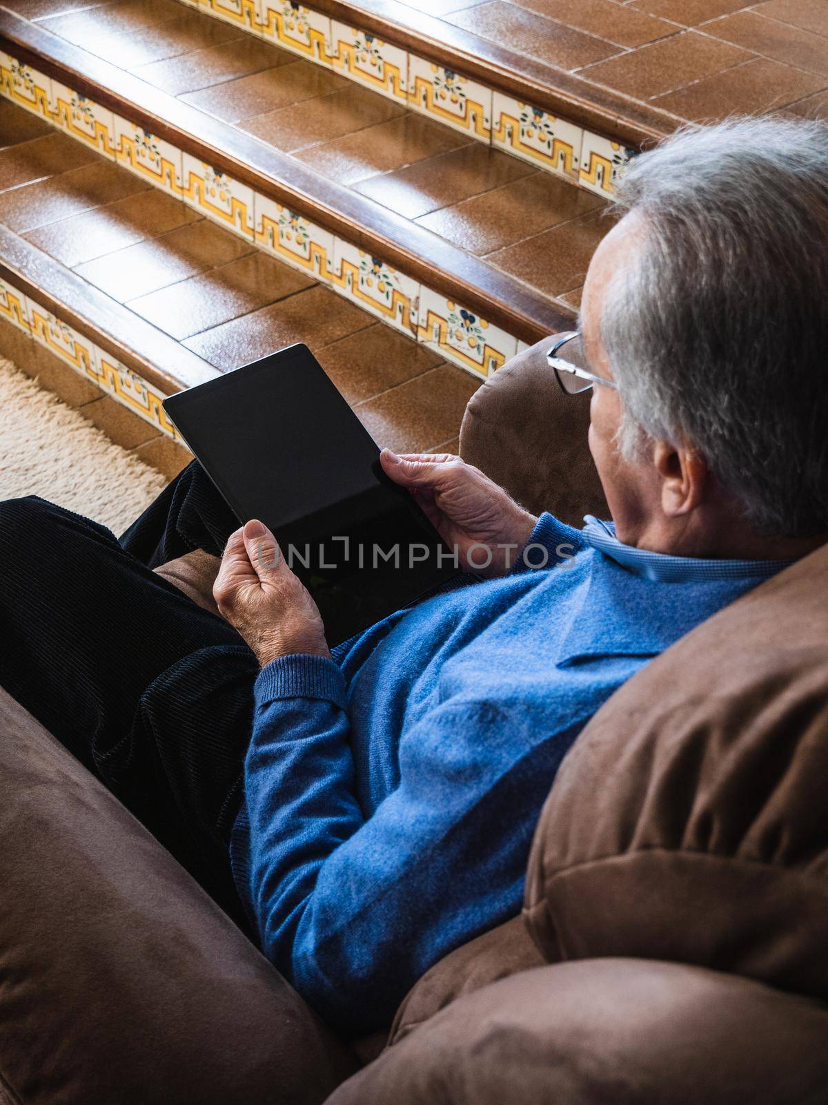 Old man looking a tablet in house by CatPhotography