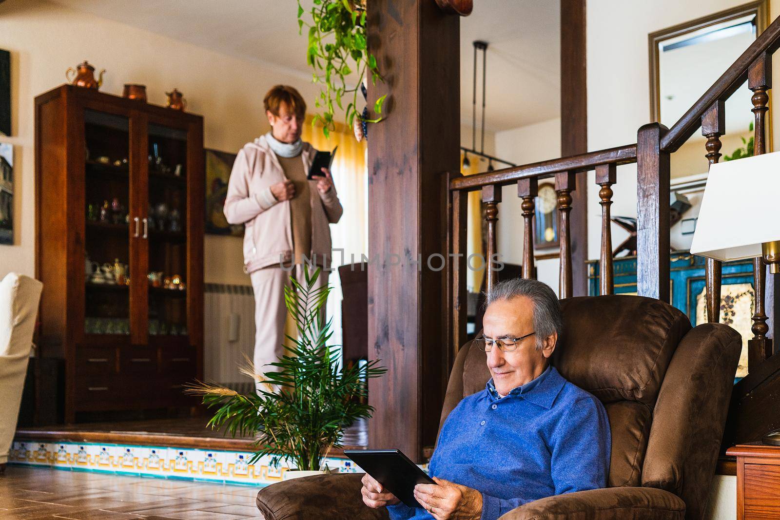 Old man looking at tablet in sofa by CatPhotography