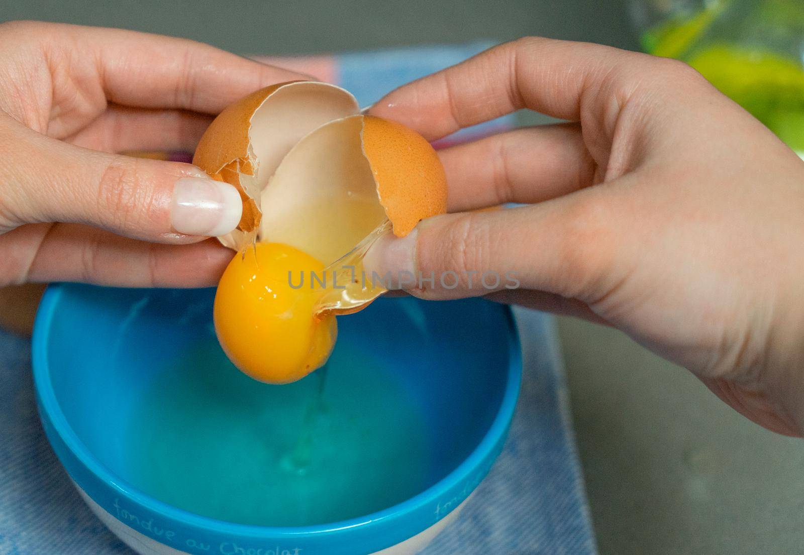 yolk inside a broken egg falling in a bowl by CatPhotography