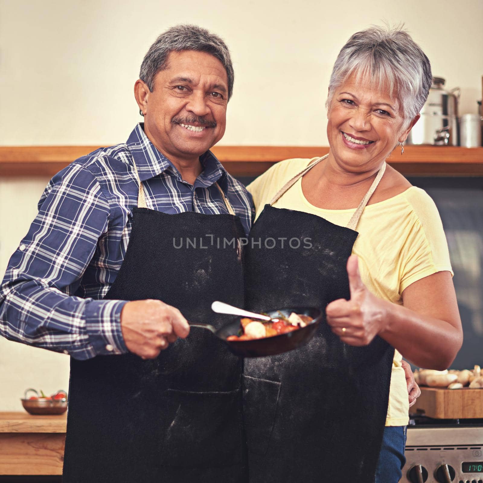 Dinner is served. Shot of a mature couple cooking together at home. by YuriArcurs