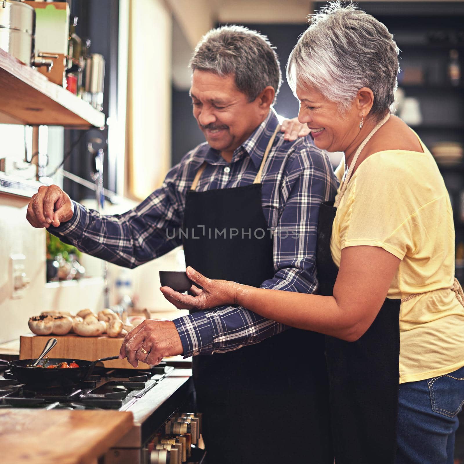 Seasoned with love. Shot of a mature couple cooking together at home. by YuriArcurs