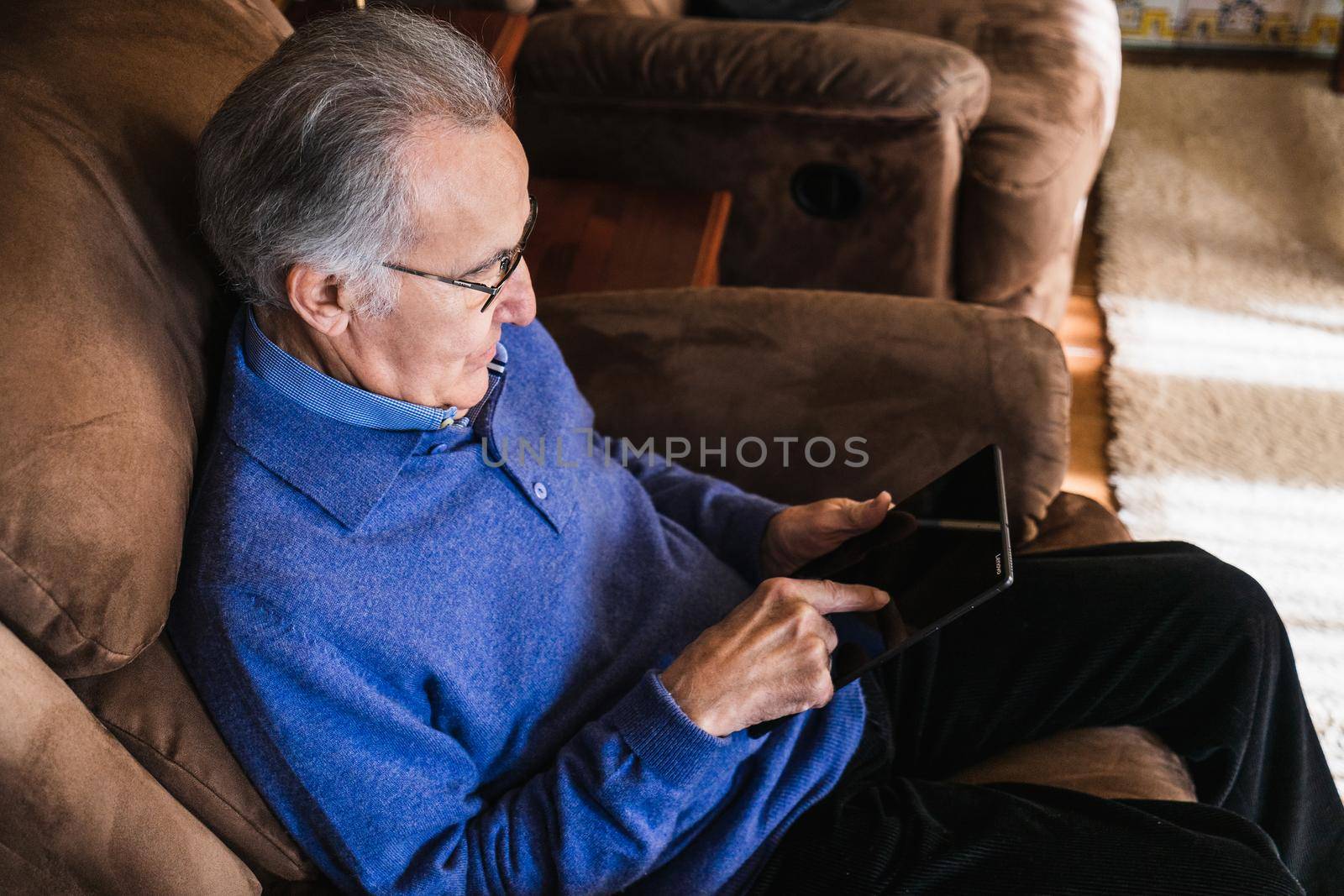 Old man looking a tablet in house by CatPhotography