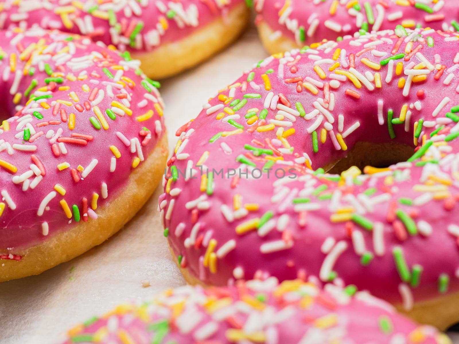 donuts poured with pink icing sprinkled with pastry topping with chopsticks.