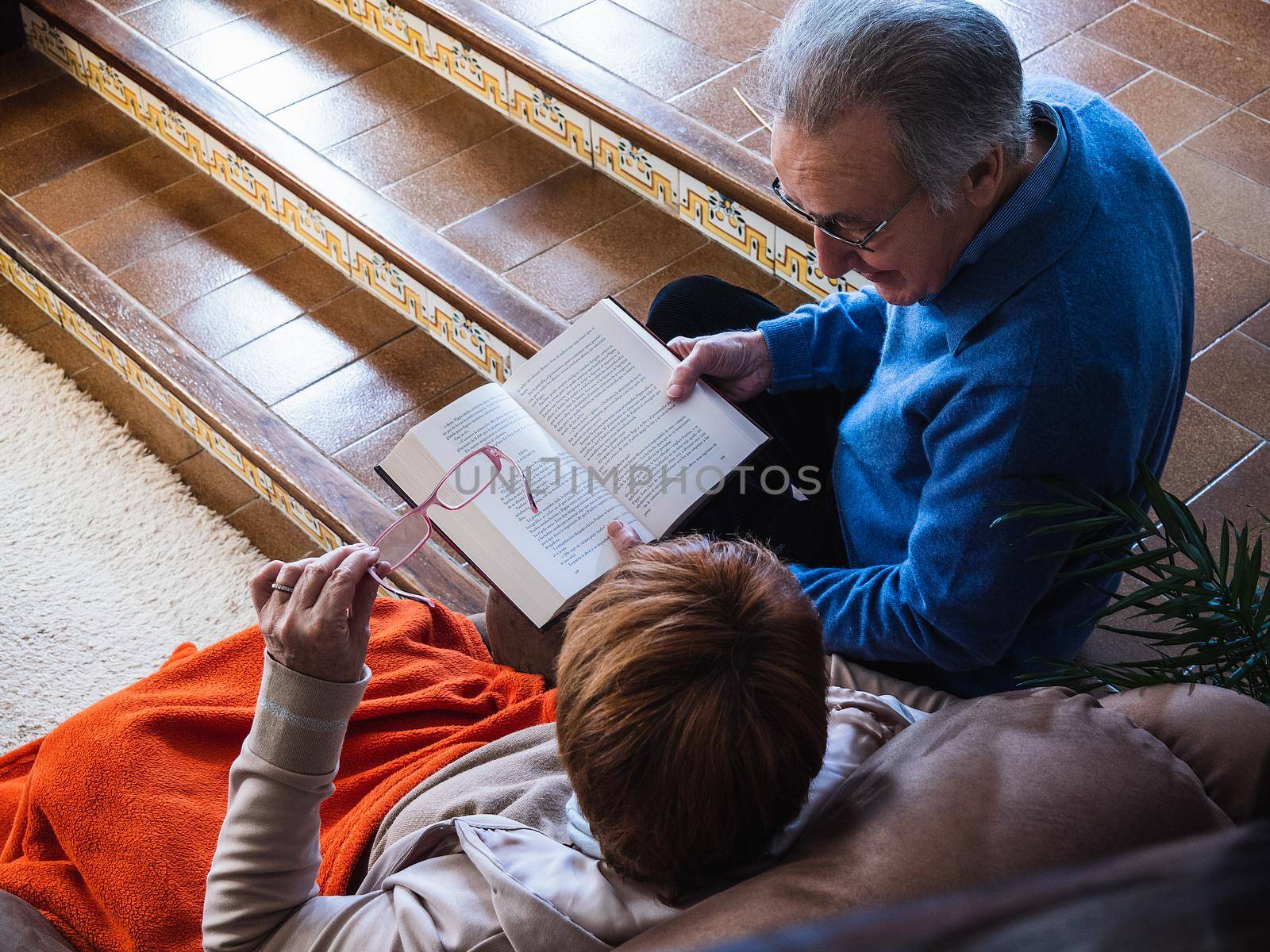 Old marriage reading a book in house by CatPhotography